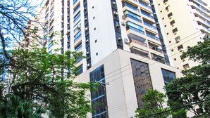 A high-rise building with multiple floors, large windows, and air conditioning units. - Apto a 200 m da Praia das Pitangueiras-guaruj SP (Guarujá)