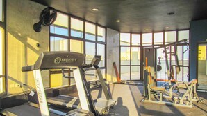A gym with treadmills, weight machines, and a large windowed wall. - Apto a 200 m da Praia das Pitangueiras-guaruj SP (Guarujá)