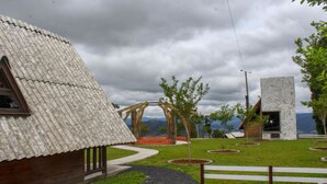 A rustic building with a corrugated metal roof, surrounded by a landscaped garden with pathways and small trees. - Chal com Wi-fi e Muito Lazer em Bom Retiro SC (Bom Retiro)