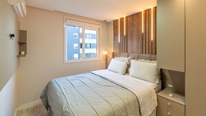 Ein Schlafzimmer mit einem großen Bett, einem Fenster, einem Nachttisch und einem Kleiderschrank.