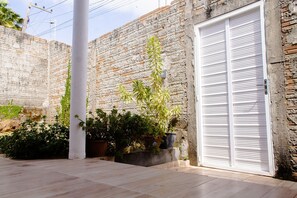 A courtyard with a white door, potted plants, and a stone wall. - Linda Casa c Wi-fi a 900m da Praia de Itatinga MA (Alcantara)