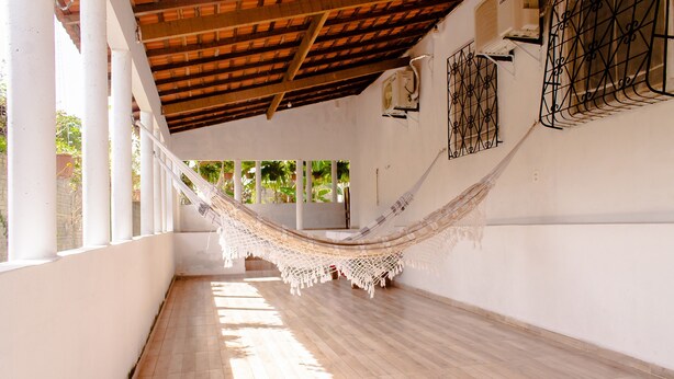 A spacious corridor with a wooden floor, white walls, and a hammock hanging from the ceiling.