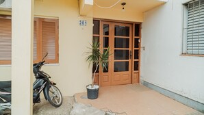 A building with a numbered door, a potted plant, and a parked motorcycle. - Timo Apto c Wifi Ar-condicionado e Garagem (Uruguaiana)