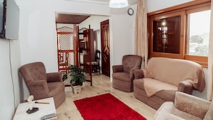 A living room with two brown armchairs, a beige sofa, a red rug, and a wooden partition with a lattice design. - Timo Apto c Wifi Ar-condicionado e Garagem (Uruguaiana)