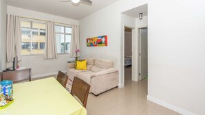 A living room with a beige sofa, a yellow table, and a ceiling fan. - Apto com Wifi e Tima Localiza o Laranjeiras RJ (Rio de Janeiro)