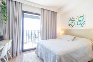 A hotel room with a bed, a desk, and a balcony. - Studio Elegante com Varanda e Tima Localiza o (São Paulo)