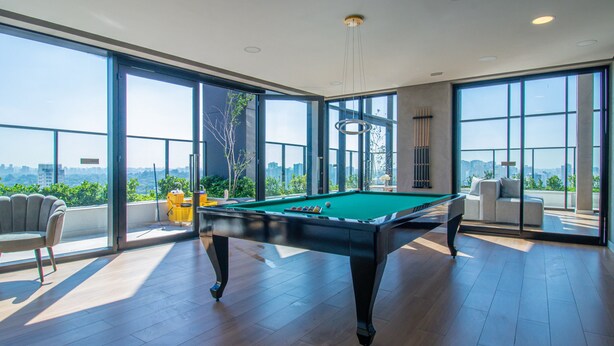 Ein geräumiges Zimmer mit Billardtisch, großen Fenstern und Blick auf die Stadt.