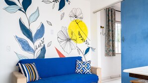 A room with a sofa, a small table, and a wall with a floral mural.