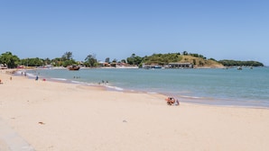 Une plage avec un ciel dégagé, une eau calme et peu de monde.