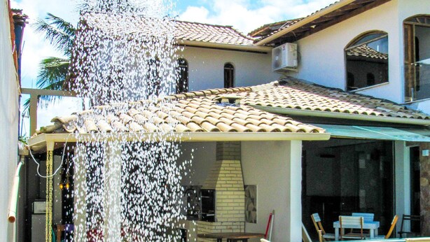 Um imóvel residencial com piscina, varanda coberta e um elemento aquático.