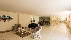 A spacious living area with a sofa, two armchairs, a coffee table, and a dining area in the background. - Apto Top Pitangueiras no Melhor Ponto do Guaruj (Guarujá)