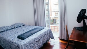 Une chambre à coucher avec un lit, un bureau en bois et une fenêtre avec des rideaux.