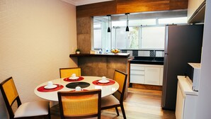 Une cuisine moderne avec un coin repas, comprenant une table ronde avec des chaises, un réfrigérateur et une fenêtre donnant sur l’extérieur.