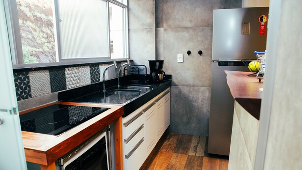 Une cuisine moderne avec un plan de travail noir, des appareils en acier inoxydable et un plancher en bois.