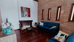 Un soggiorno con camino, un divano blu, un tavolino in legno e un quadro appeso al muro.