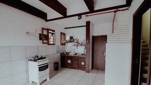 Una cucina con piastrelle bianche, un piano cottura bianco, mobili in legno e una scala che conduce in un'altra stanza.