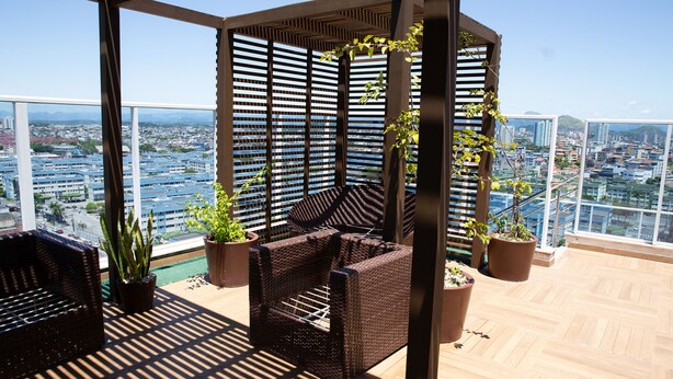 Un balcone con mobili in vimini, piante in vaso e vista sulla città.