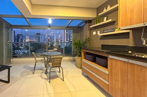 A modern kitchen with a city view, a dining area with chairs, and a small table. - Excelente Apto a 50m do Metr Butant em S o Paulo (São Paulo)