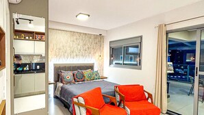 A modern bedroom with a bed, a desk, and a chair. There is a window and a door leading to a balcony. - Excelente Apto a 50m do Metr Butant em S o Paulo (São Paulo)