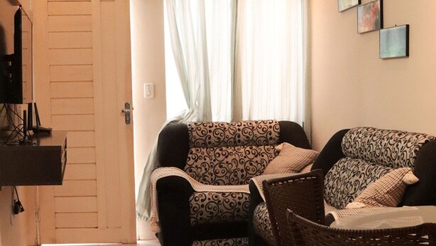 A living room with a sofa set, a ceiling fan, a rug, and a television on a stand. - Casa c Wifi e Tima Localiza o em Barreirinhas MA (Barreirinhas)