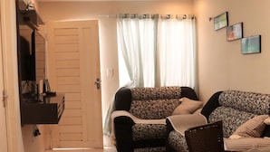 A living room with patterned sofas, a glass coffee table, and a door leading to another room. - Casa c Wifi e Tima Localiza o em Barreirinhas MA (Barreirinhas)