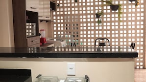 A kitchen with a black countertop, a microwave, a blender, and a coffee maker. There are potted plants on the wall and a chair. - Casa c Wifi e Tima Localiza o em Barreirinhas MA (Barreirinhas)