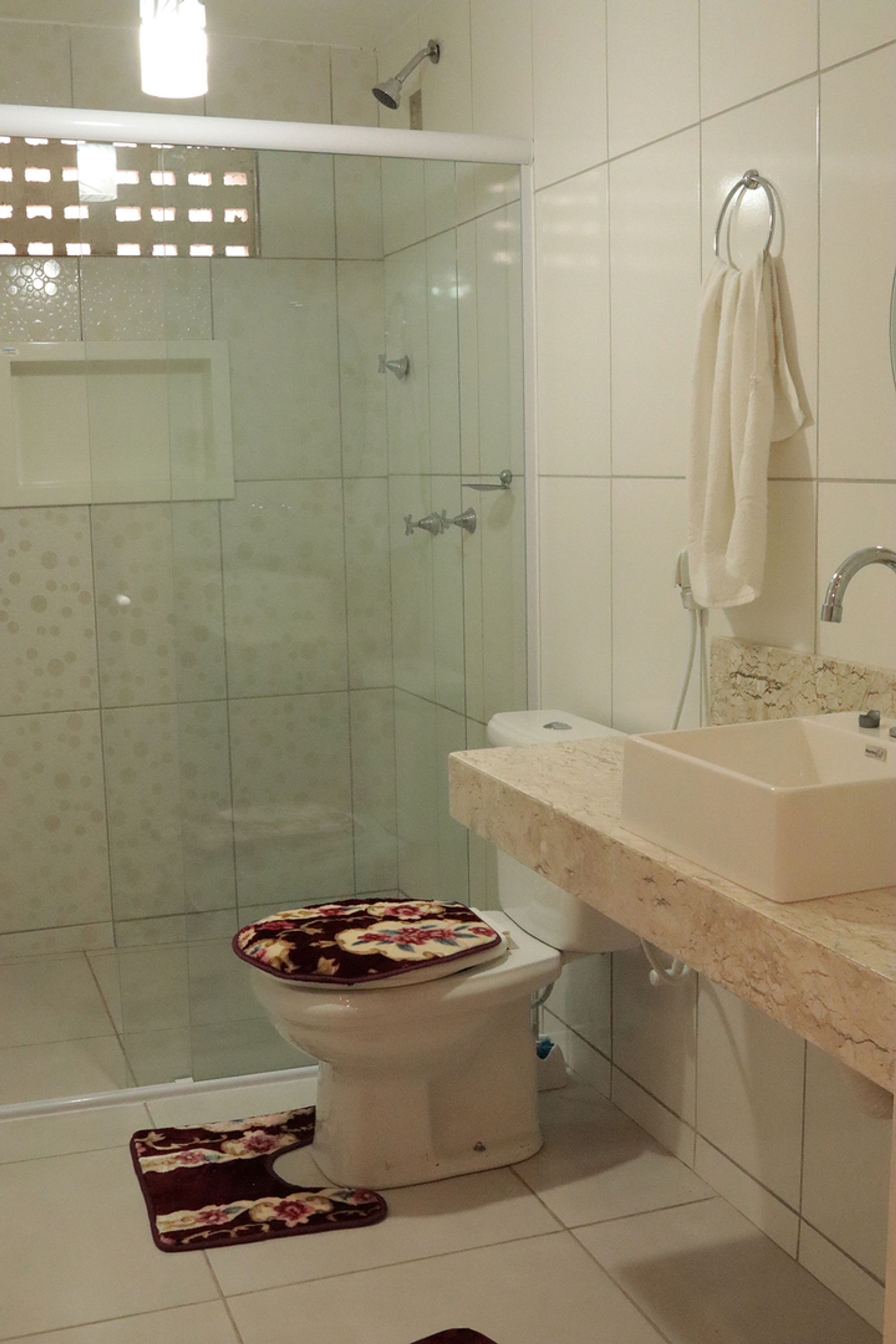 A bathroom with a shower, toilet, sink, and a towel hanging on the wall.