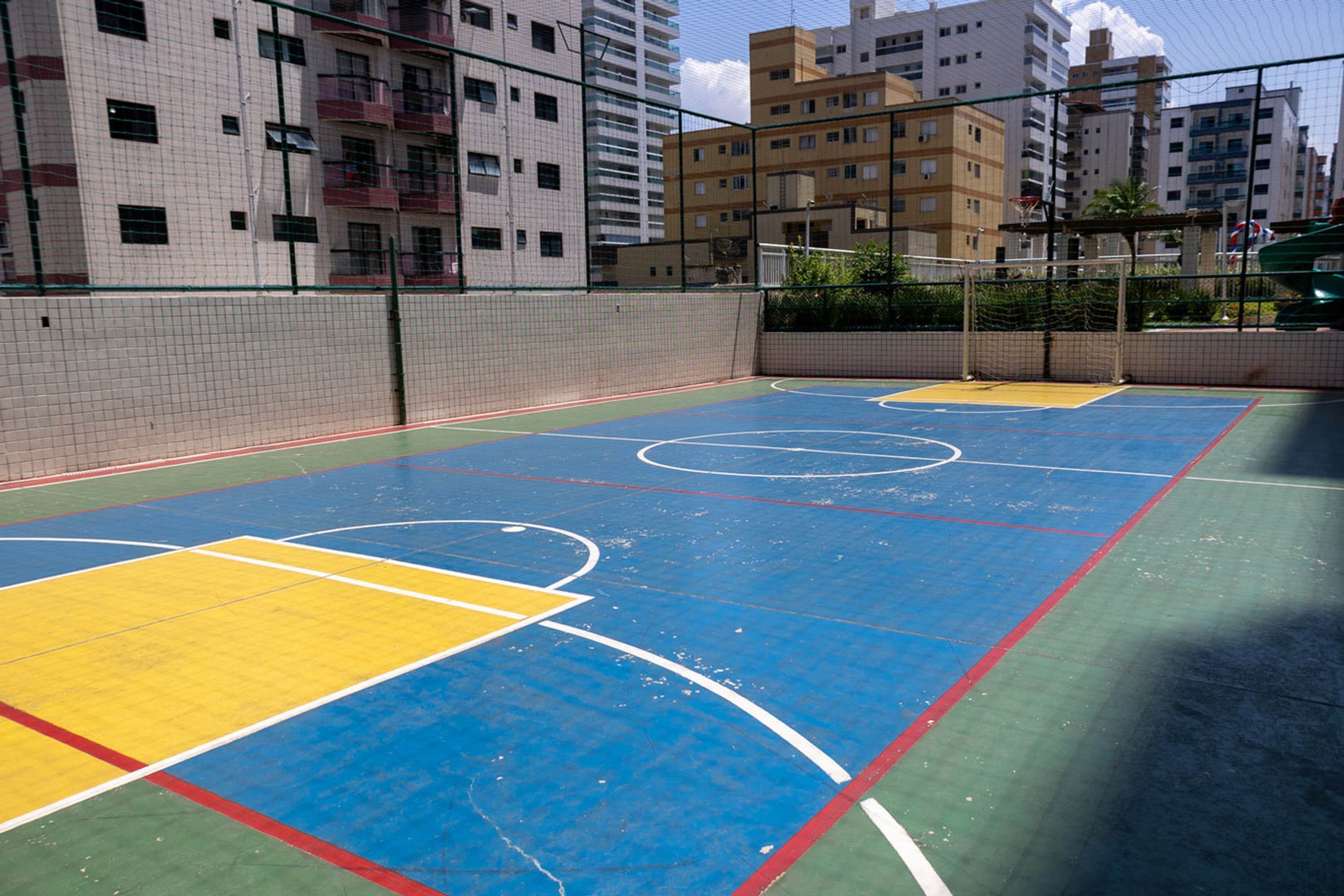 Ein Basketballplatz im Freien mit Netz, umgeben von einem Zaun.