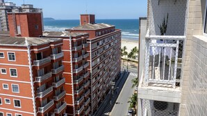 A multi-story hotel with balconies overlooking a beach and ocean. - Apto Confort vel a 150m do mar Completo com Lazer (Praia Grande)