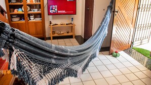 Una hamaca en una habitación con televisión, mueble de madera y una puerta.