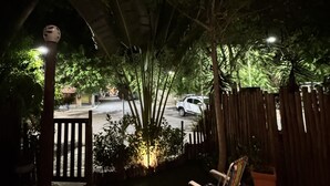 Un patio con mesa y sillas de madera, rodeado por una valla de madera y abundante vegetación.