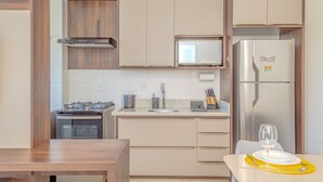 A modern kitchen with wooden cabinets, a stainless steel refrigerator, a microwave, and a stove. - Apartamento Completo em Trindade Perto da Ufsc (Florianópolis)
