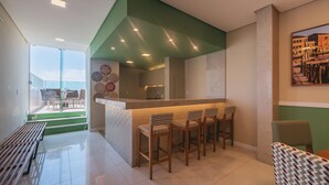 Eine moderne Küche mit grüner Akzentwand, einer Bar mit vier Hocker und einem Essbereich mit einer Bank und Stühlen.