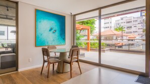Una habitación moderna con un gran ventanal, una mesa de comedor con sillas y un cuadro abstracto y llamativo.