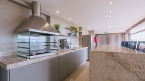 Una cocina moderna con campana de acero inoxidable, parrilla integrada y máquina de café.