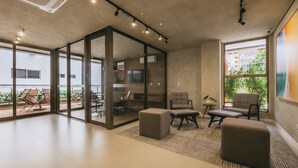 Un interior moderno con un separador de vidrio, asientos cómodos, un televisor de pantalla plana y vistas a zonas verdes.