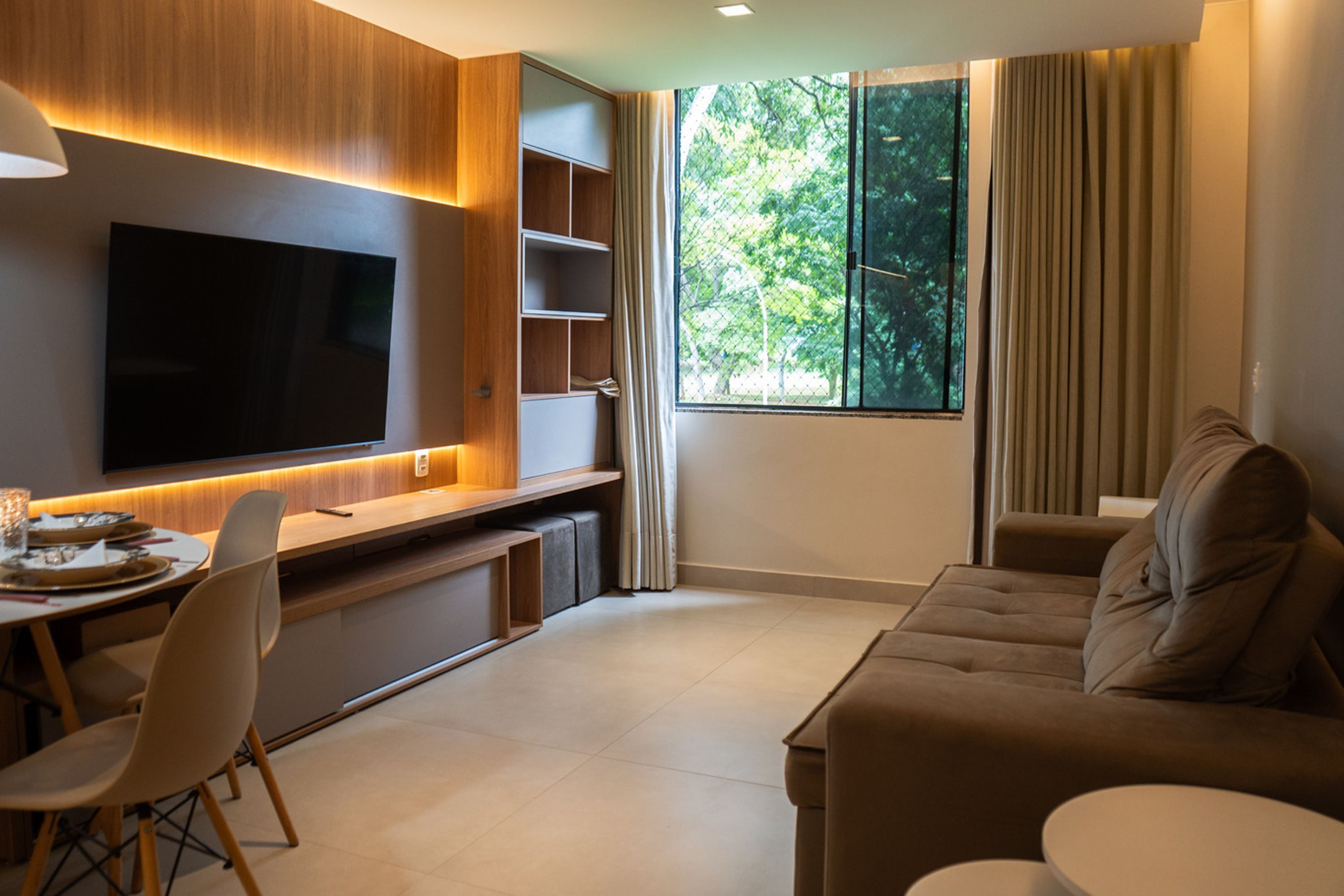 A modern living room with a flat-screen TV, a dining area, and a sofa.