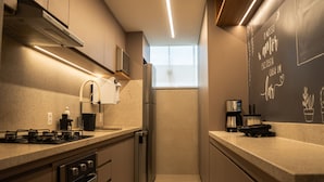 A modern kitchen with stainless steel appliances, a window providing natural light, and a chalkboard with writing on the wall. - Apto c Wi-fi Tima loc Prox ao Eixo Monumental (Brasília)