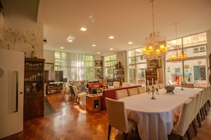 Amplia sala de estar con una mesa de comedor lista para seis personas, rodeada de asientos cómodos.
