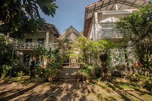 Una casa tradicional con jardín, una escalera que lleva a la entrada y un balcón.