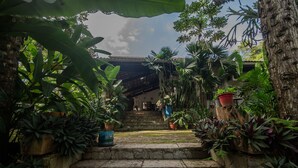 A stone staircase leading to a building with a tiled roof, surrounded by lush tropical plants. - Ch Cara Completa c Wifi Piscina Sauna Churrasq (Guaramiranga)
