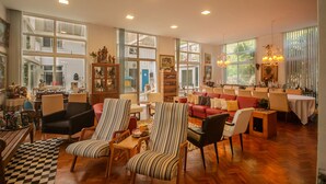 A spacious living room with a large window, a dining area, and a kitchen visible through the glass doors. - Ch Cara Completa c Wifi Piscina Sauna Churrasq (Guaramiranga)