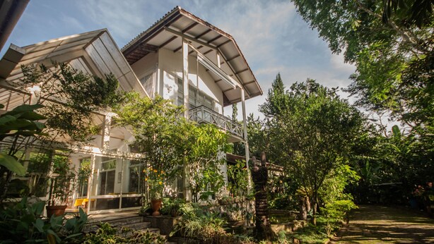 A two-story house with a balcony, surrounded by lush greenery and a garden. - Ch Cara Completa c Wifi Piscina Sauna Churrasq (Guaramiranga)