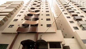 A high-rise building with multiple balconies, a tiled facade, and a central entrance with a canopy.