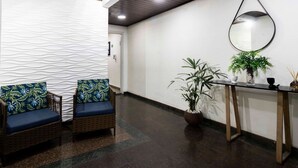 A reception area with two wicker chairs with blue cushions, a reception desk with a mirror, and potted plants.