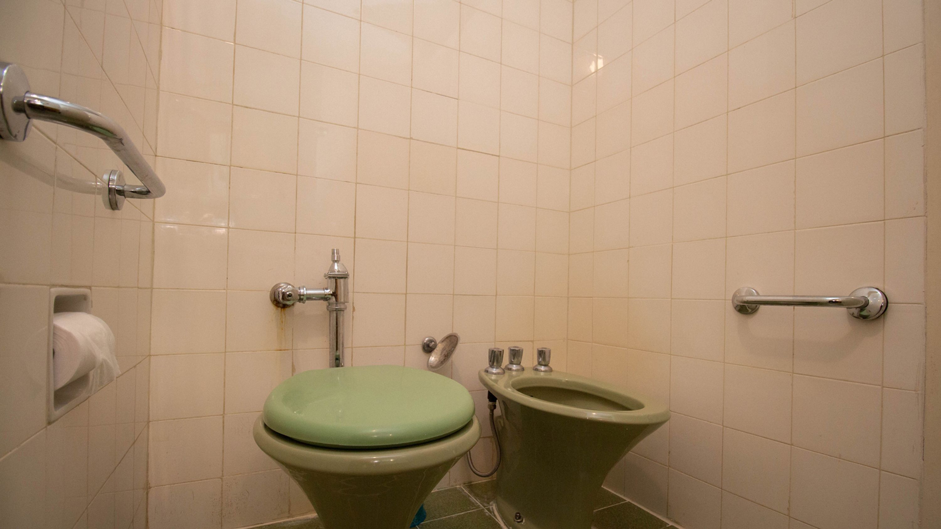 Et badeværelse med toilet, bidet og gelændere.