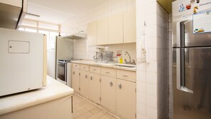 A kitchen with white cabinets, a stainless steel refrigerator, and a stove. - Apto com boa Localiza o Garagem e Ar-condicionado (Brasília)