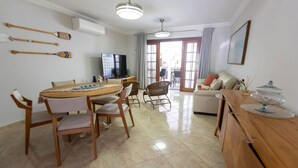 A modern living room with a dining area, a sofa set, a TV, and a view to the outside. - Casa em Condom nio com Piscina Wi-fi e Garagem (Guarujá)