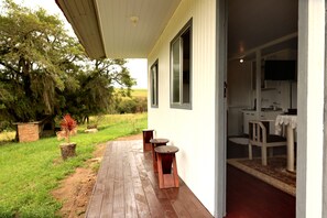 Une terrasse en bois avec un espace salon extérieur, un coin cuisine comprenant une table et des chaises, et une vue sur le paysage environnant.