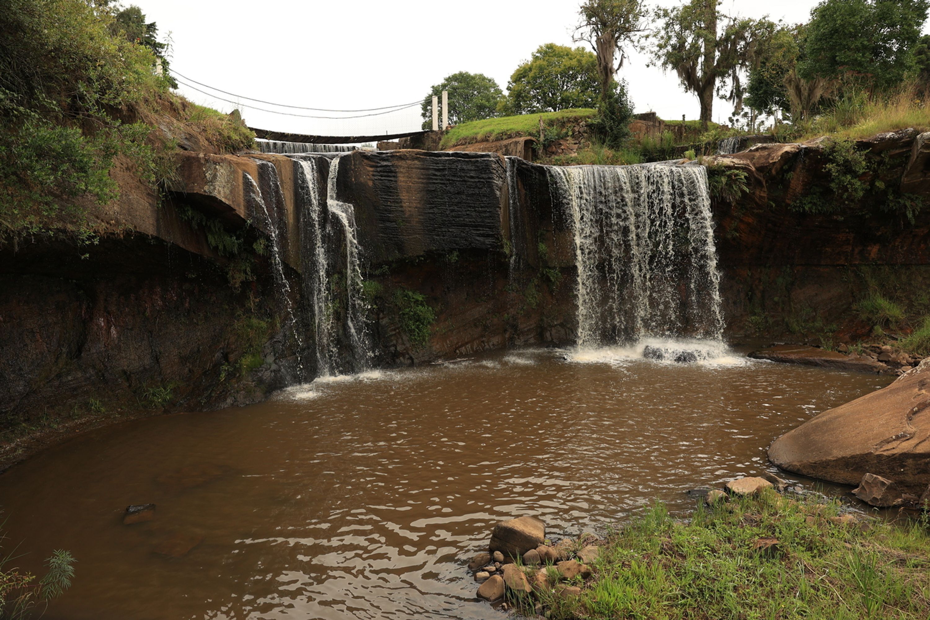 Una cascada que se precipita en un río, rodeado de terreno rocoso y vegetación.
